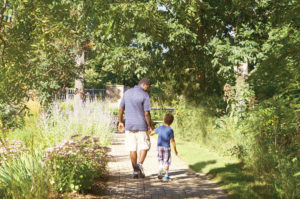 Father and son hold hands while walking on the brick walk