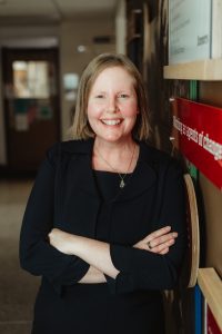 Dr. Jaime Goldberg with folded arms leaning against a wall