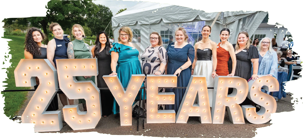 agrace staff at the 25 year anniversary gala behind a lit 25 year sign